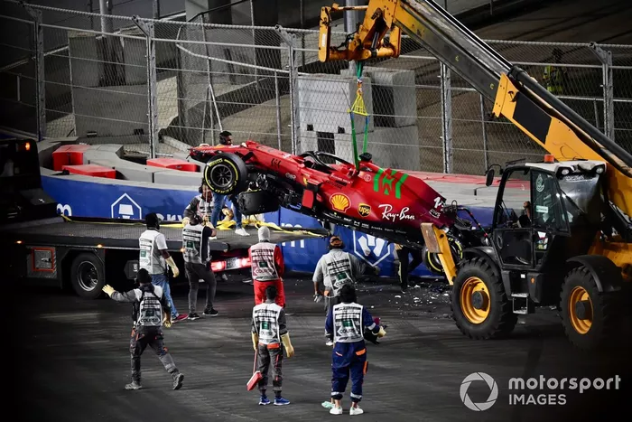 Los oficiales de pista retiran el coche dañado de Charles Leclerc, Ferrari SF21, del circuito