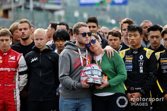 La madre de Anthoine Hubert está de pie con su hermano sosteniendo su casco de carrera