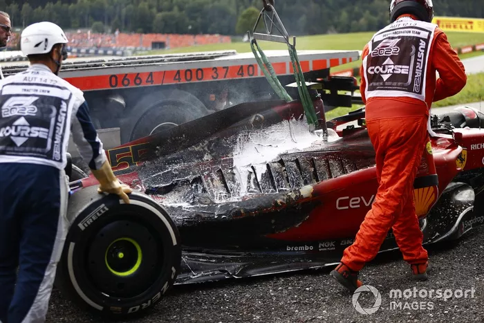 Los oficiales de pista retiran del circuito el coche incendiado de Carlos Sainz, el Ferrari F1-75