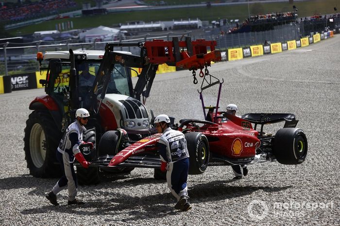 Los oficiales de pista retiran el coche incendiado de Carlos Sainz, Ferrari F1-75