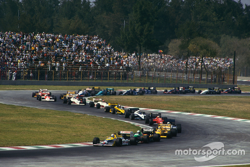 Nigel Mansell, Williams FW11B Honda, leads Teo Fabi, Benetton B187 Ford, Ayrton Senna, Lotus 99T Honda, and the rest of the field on the first lap