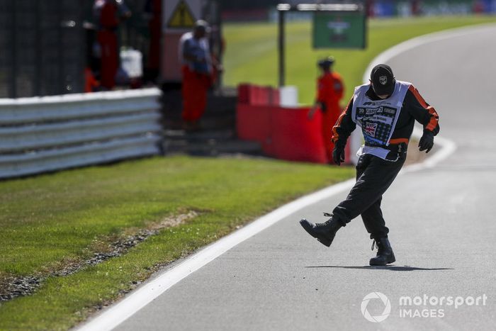 Un oficial de pista saca algunos escombros del circuito