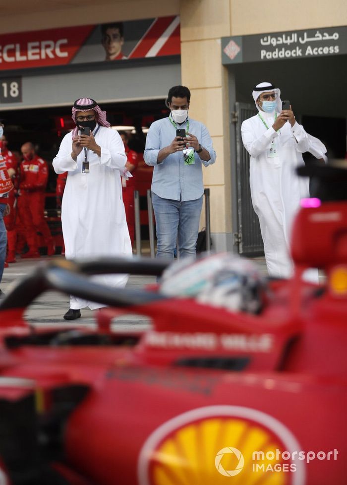 VIPs toman una foto de Charles Leclerc, Ferrari SF21, en el pit lane