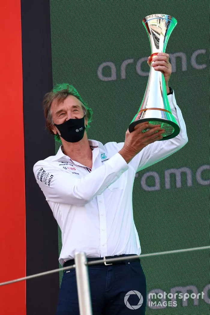 El encargado de Mercedes de recoger el trofeo levanta el trofeo de constructores