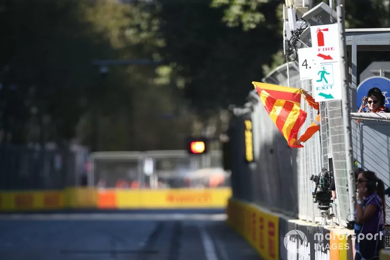 Les commissaires déploient les drapeaux rouge et jaune d'état de la piste.
