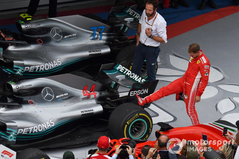 Sebastian Vettel, Ferrari regarde le pneu arrière de la voiture de Lewis Hamilton, Mercedes-AMG F1 W09 dans le Parc Fermé