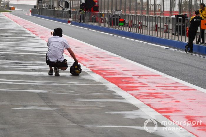 Un miembro del equipo McLaren intenta secar el pit lane