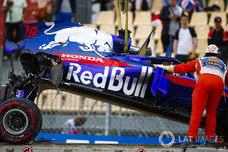 Oficiales retiran el automóvil dañado de Brendon Hartley, Toro Rosso STR13, del circuito cuando la caja de cambios cuelga de la parte posterior