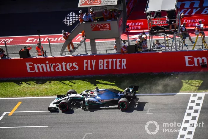 El ganador de la carrera Lewis Hamilton, Mercedes AMG F1 W10 cruza la línea de llegada con la bandera a cuadros ondeando.