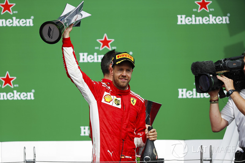 Sebastian Vettel, Ferrari, is filmed raising his winner's trophy on the podium